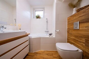 vana s dřevěná podlaha, skříňka pod dřez, přirozené světlo, zrcadlo, a toaleta