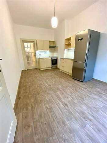 kuchyně s sporák, dřevěná podlaha, krémové barevné skříňky, lednička, a backsplash